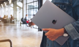 person carrying Mac laptop