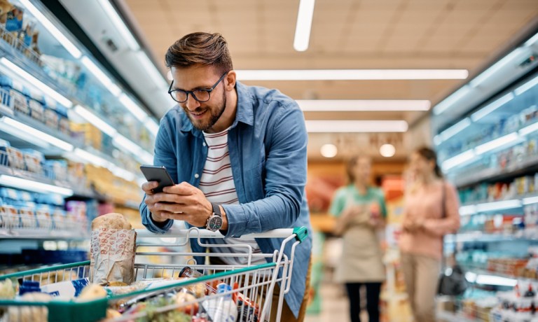 man grocery shopping in store with phone