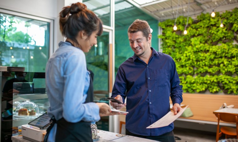 man paying restaurant tab with phone